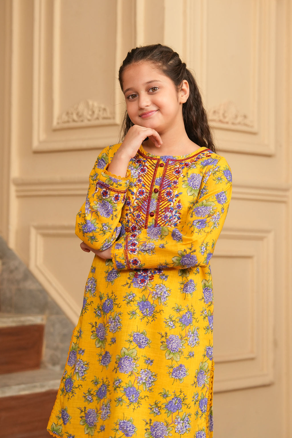 Young girl wearing a yellow floral dress indoors