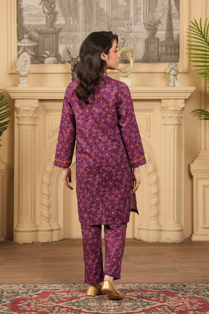 Woman wearing a purple floral outfit standing in a room with decorative elements.