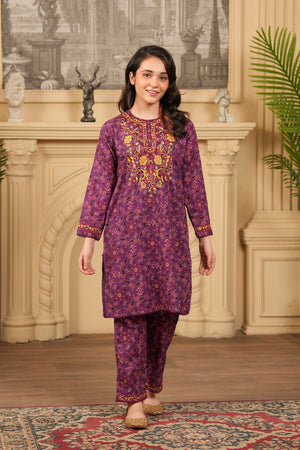 Woman wearing a purple embroidered traditional outfit in a decorated room.