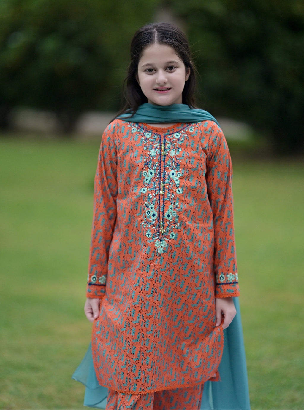 Girl wearing orange and blue floral printed traditional dress from Nims Apparel standing outdoors