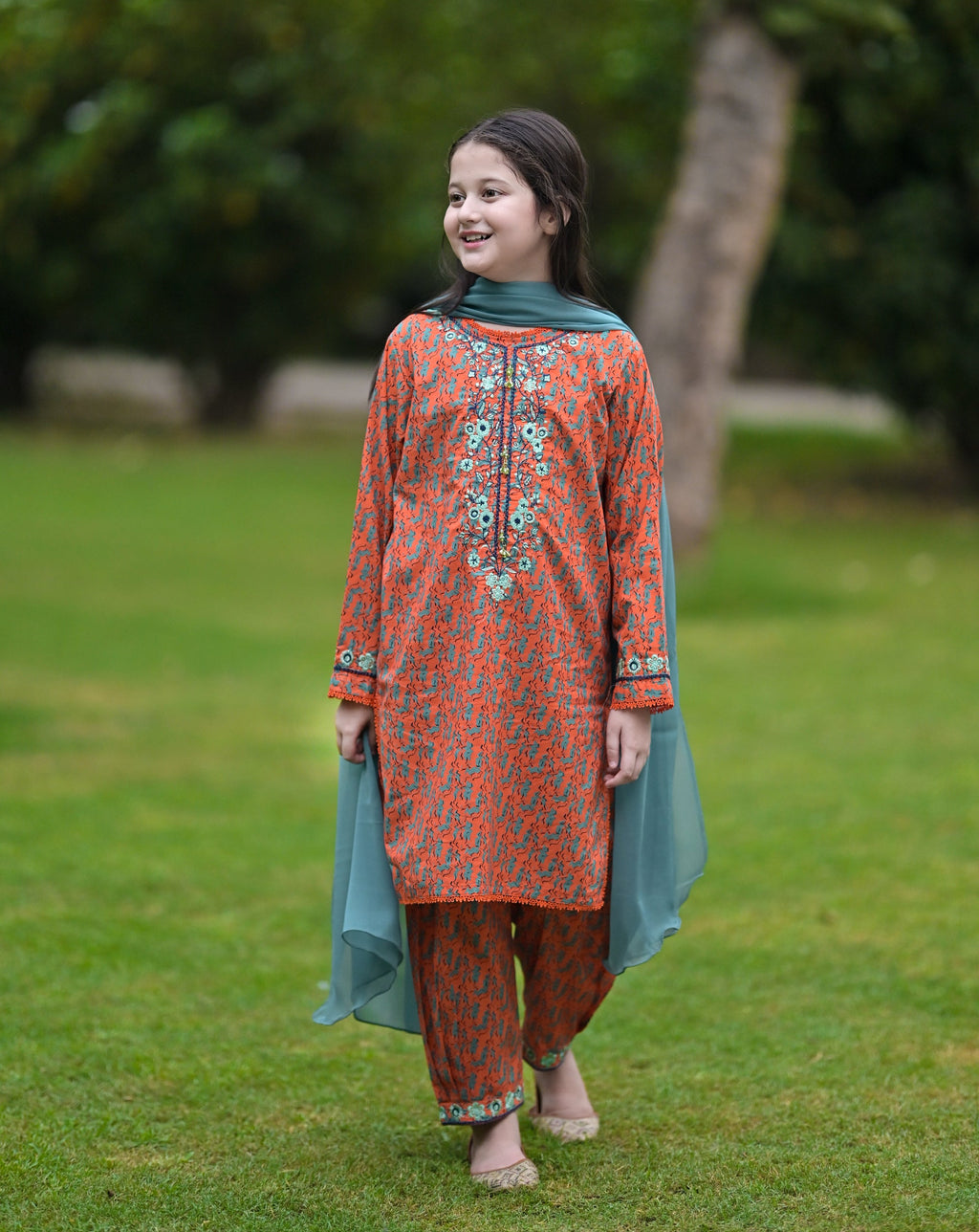 Girl wearing Nims Apparel orange floral embroidered suit with teal dupatta and matching pants outdoors