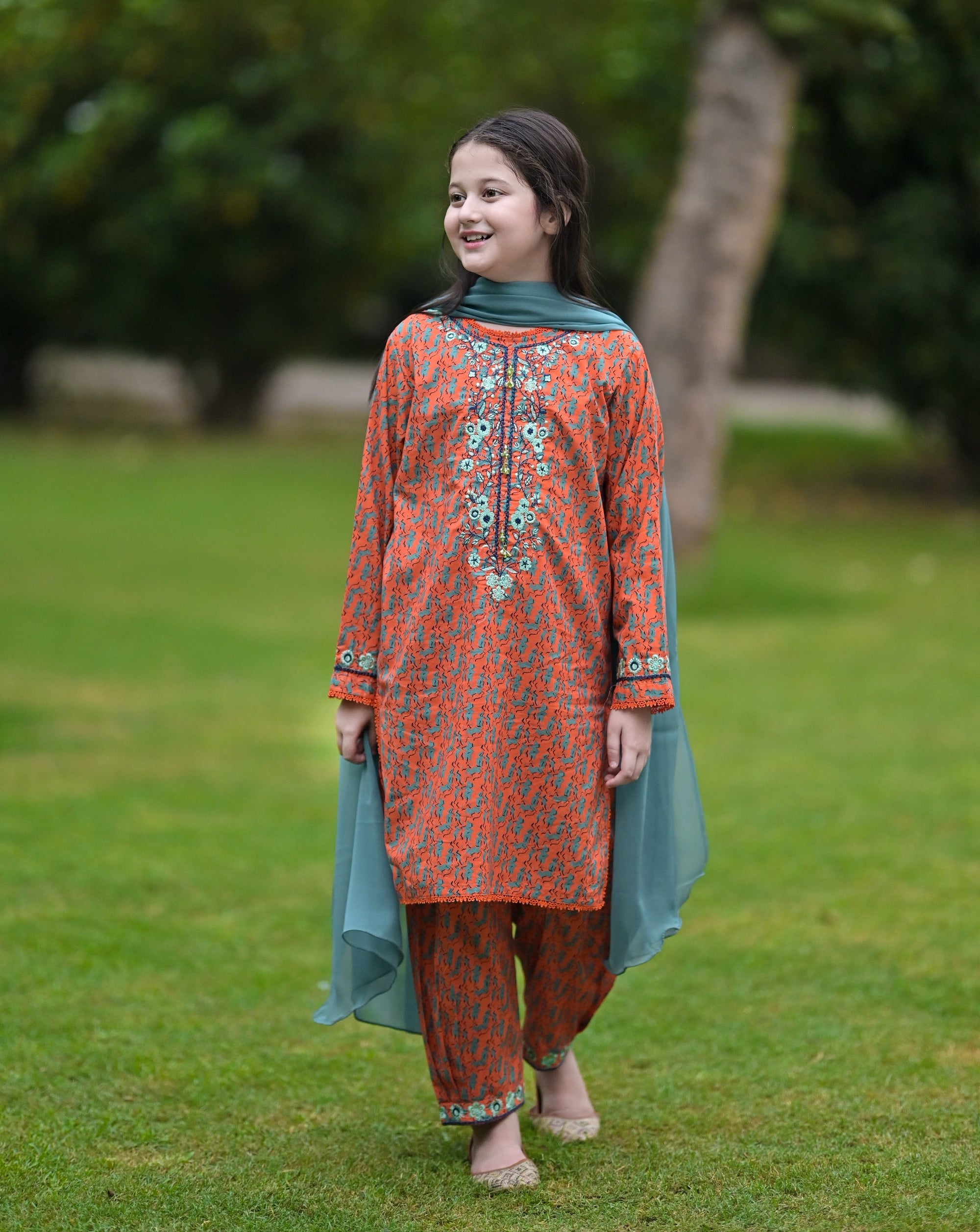 Girl wearing Nims Apparel orange floral embroidered suit with teal dupatta and matching pants outdoors